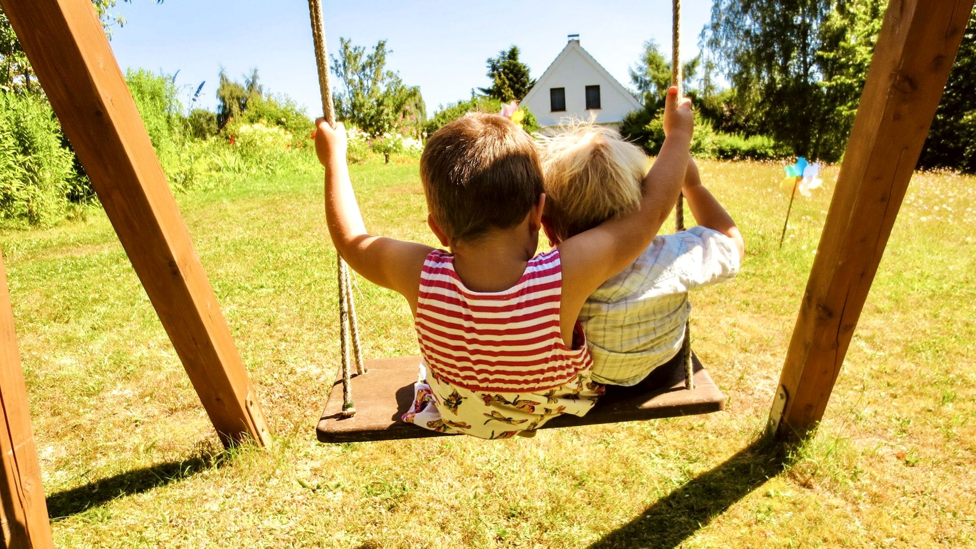 Wooden backyard swing set assembled on a sunny green lawn
